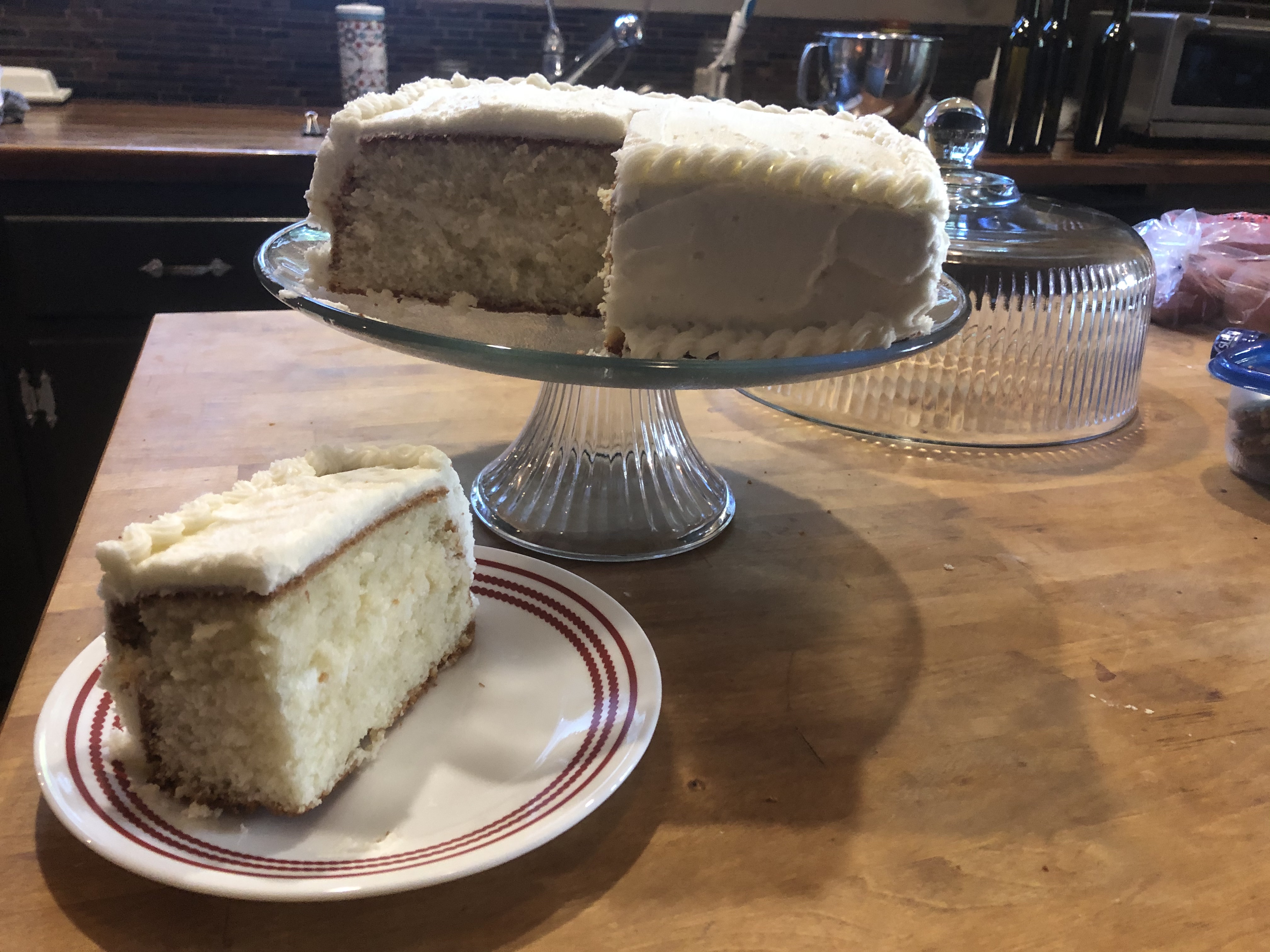Square white cake with frosting with one slice on a plate next to it