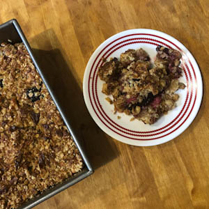 Berry crisp in pan next to piece on plate
