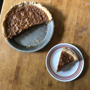 Chess pie with piece of pie on plate next to pie pan